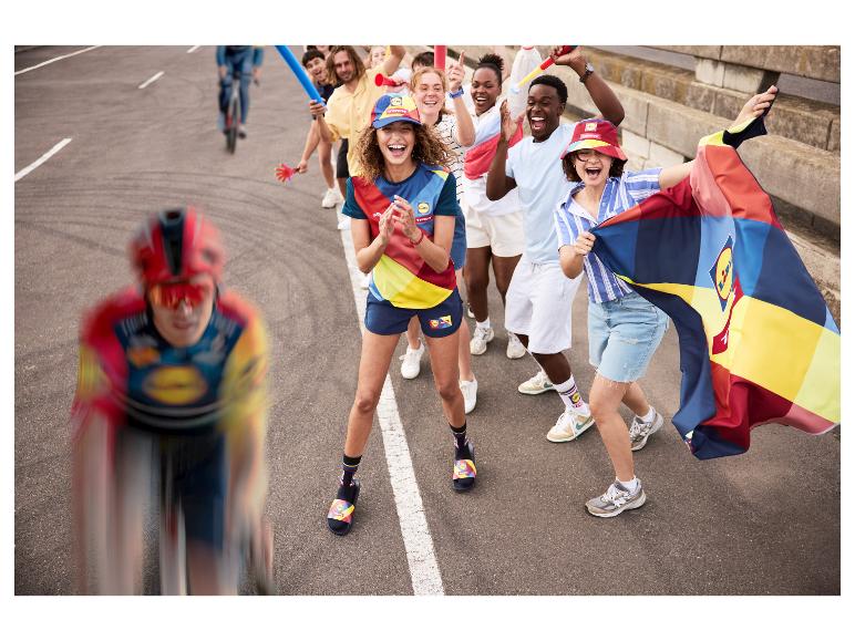 Cyclistes et fans acclamant en tenue de sport colorée, chapeaux et chaussettes avec un drapeau.