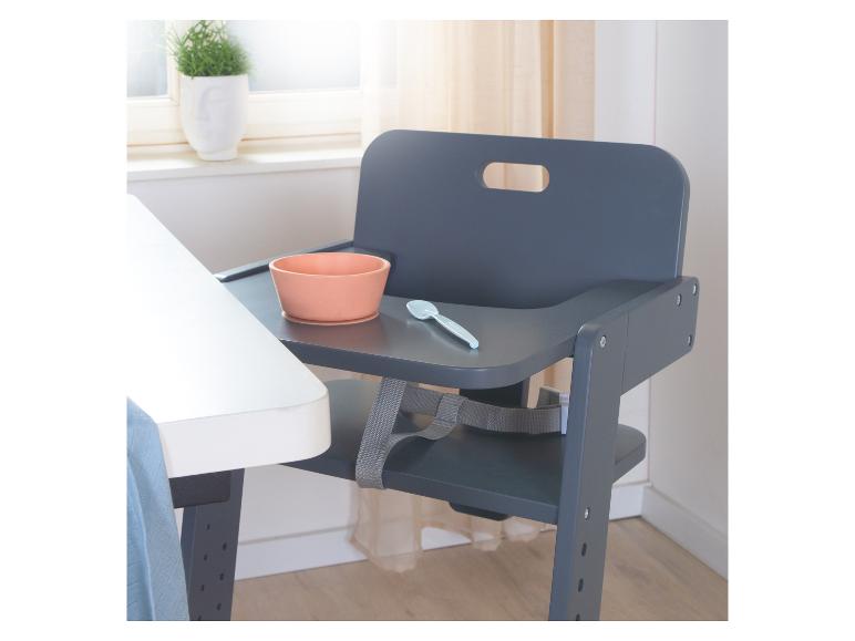 Chaise haute gris foncé avec un bol couleur pêche et une cuillère bleu clair sur le plateau.