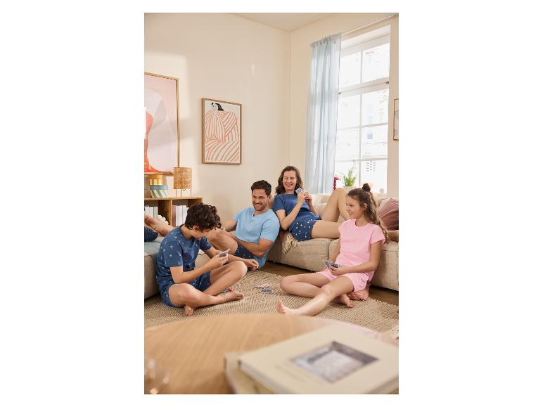 Famille en pyjama jouant aux cartes dans le salon.