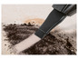 Un embout d'aspirateur noir aspire la saleté d'un tapis beige.