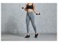 Une femme en leggings gris et un soutien-gorge de sport noir s'entraîne avec des haltères.