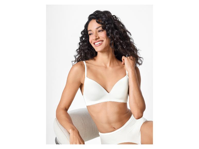 Femme en soutien-gorge et culotte blancs, assise et souriante.