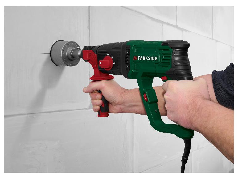 Un homme utilise une perceuse à percussion Parkside pour percer un mur.