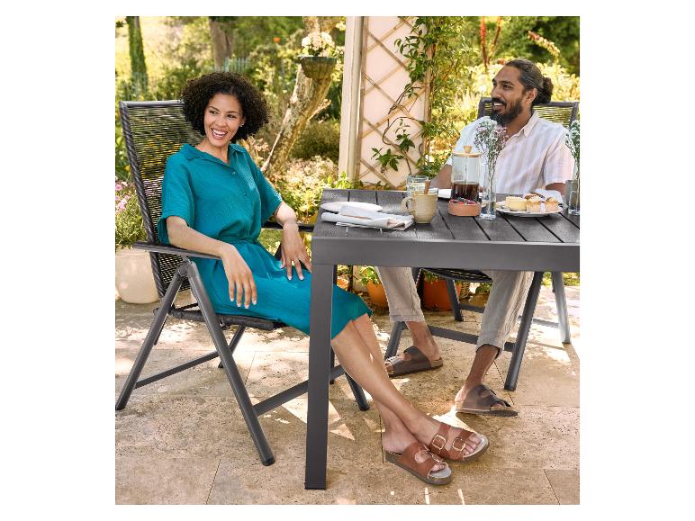 Deux personnes se détendent autour d'une table de jardin avec des chaises en osier.