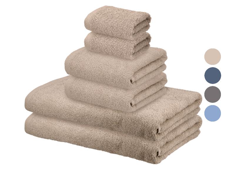 Un ensemble de serviettes beiges de différentes tailles empilées, avec des échantillons de couleur sur le côté.