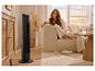 Femme se relaxant sur un canapé avec un ventilateur tour, une télécommande et une boisson.