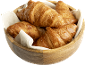Croissants au beurre dorés et feuilletés dans un bol en bois avec une serviette blanche.