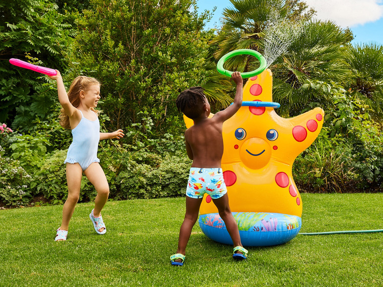 Deux enfants jouent avec un jouet d'eau gonflable en forme d'étoile de mer dans le jardin.