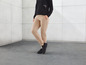 Pantalon beige avec des baskets noires.