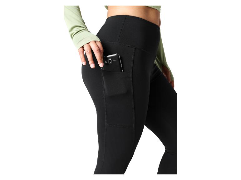 Femme en legging noir avec un téléphone dans la poche latérale et un haut vert clair