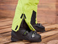 Une paire de chaussures de ski noires avec des jambes de pantalon de ski jaunes.