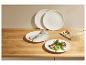 Assiettes blanches avec un plat de viande et légumes, couverts et une planche à découper en bois.