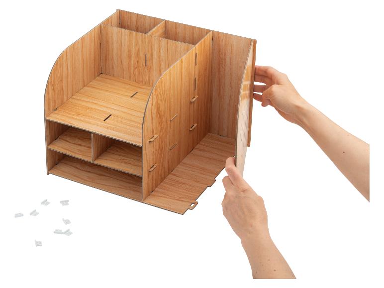 Mains assemblant un organiseur de bureau en bois avec plusieurs compartiments et étagères.