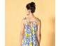 Une femme porte une robe blanche avec des citrons jaunes et des détails bleus.