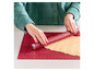 Un rouleau à pâtisserie rouge sur un tapis de cuisson rouge avec de la pâte.