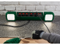 Multiprise verte avec lumières et une personne utilisant un pistolet thermique et un grattoir.