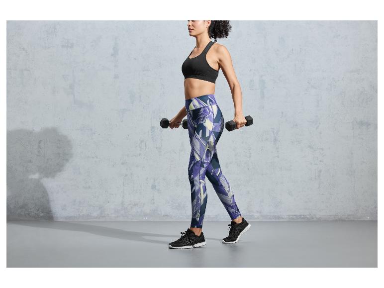 Une femme portant un soutien-gorge de sport noir et un legging à imprimé soulève des poids.