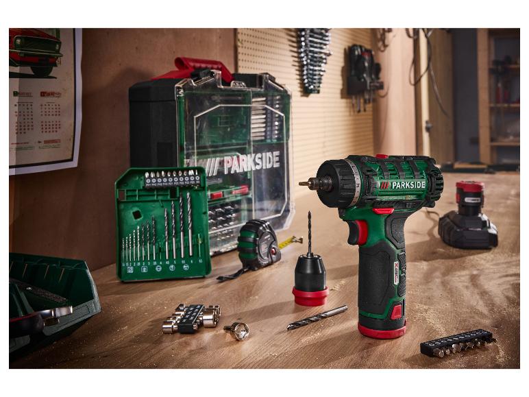 Perceuse-visseuse sans fil PARKSIDE 12 V avec batterie, chargeur et accessoires sur un établi en bois.