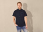 Homme portant une chemise à manches courtes bleu marine cintrée et un jean.