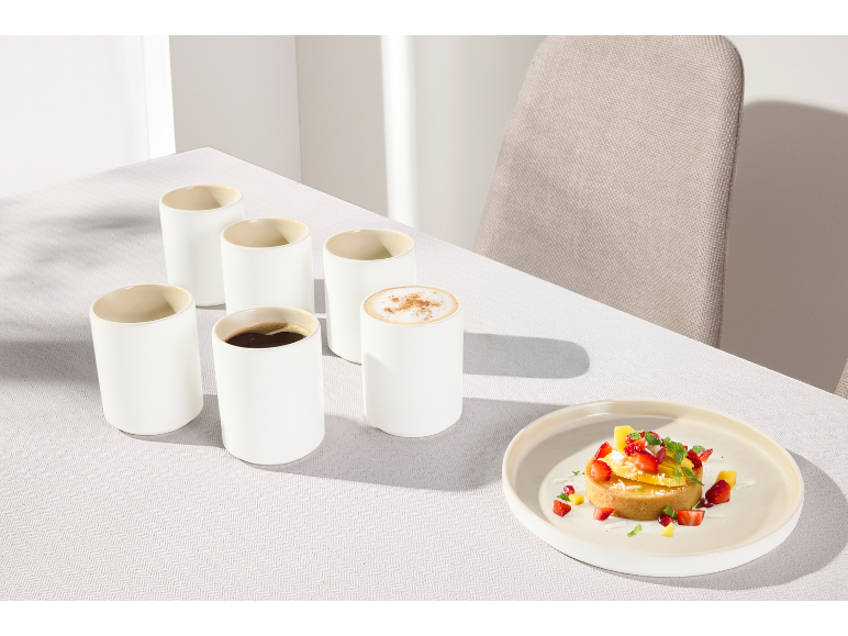 Ensemble de tasses en céramique sans anse et assiette avec dessert sur la table.