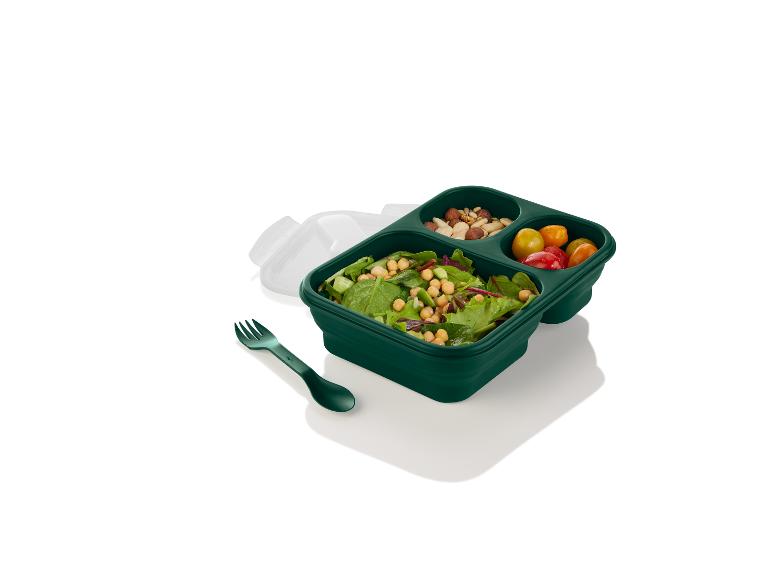 Boîte à lunch verte avec une salade, des noix et des tomates cerises.