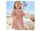 Robe rose en gaze de coton pour enfant, jouant avec une girouette colorée près de la mer.
