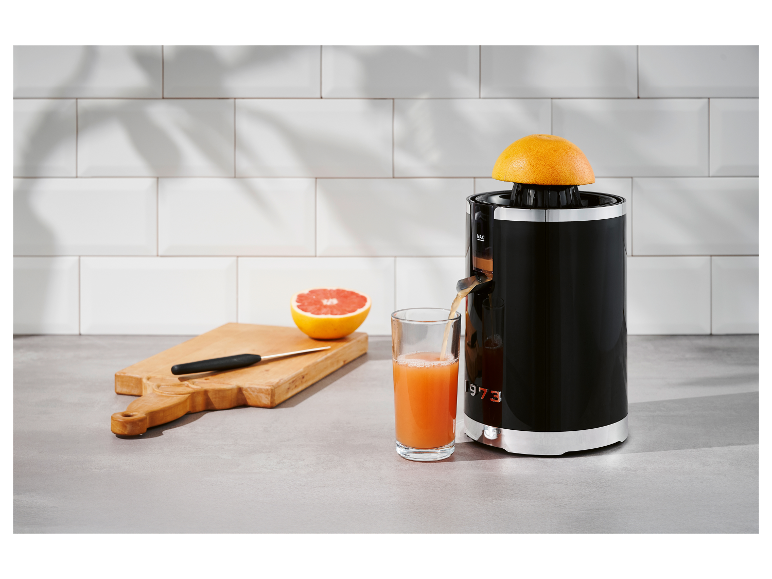 Presse-agrumes rétro 1973 exprimant du jus de pamplemousse dans un verre.