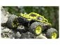 Un monster truck Extron jaune et noir grimpe sur des rochers.