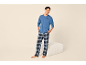 Homme souriant en pyjama bleu et pantalon à carreaux, avec un motif 'Coffee is my therapy'.