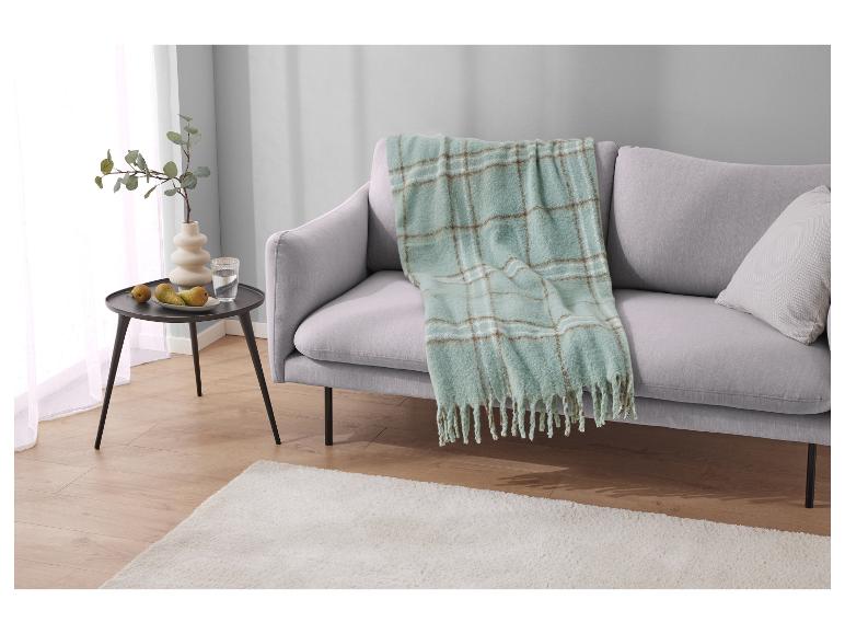 Un canapé gris clair avec une couverture à carreaux verts et bruns.