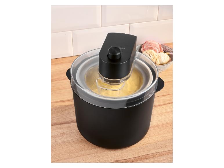 Machine à glace noire avec de la glace jaune et un bol de glace en arrière-plan.