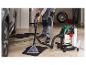 Homme nettoie les tapis de voiture avec un aspirateur Parkside dans un garage.