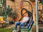 Un homme se relaxe dans un fauteuil suspendu dans un jardin.