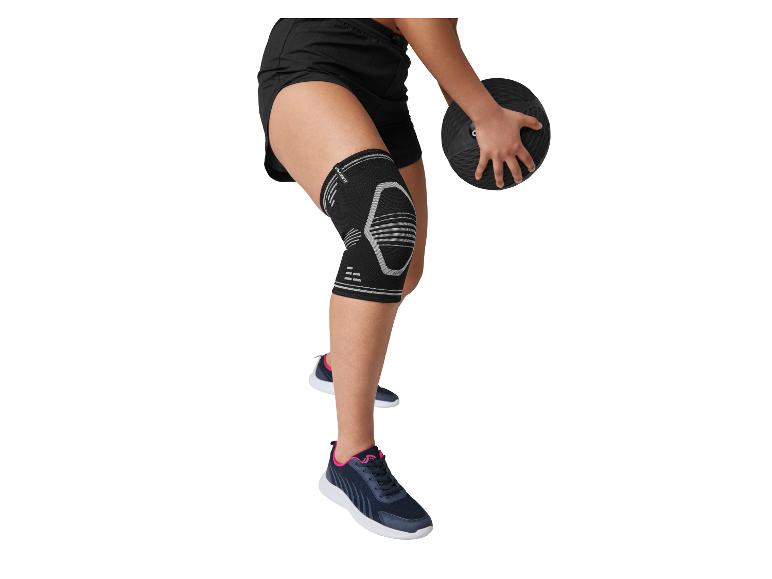 Personne portant une genouillère noire et un short noir, tenant un ballon de médecine noir.