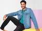 Un homme portant une veste en jean, un t-shirt et un jean.