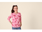 Jeune fille portant un pull rose à motifs de nœuds et un jean.