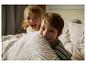 Deux enfants jouent au lit, l'un se cachant derrière une couverture.