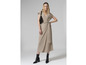 Une femme portant une robe beige, des bottes noires et un sac noir.