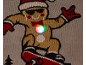 Détail d'un pull de Noël gris avec un bonhomme en pain d'épice sur un skateboard et une lumière LED.