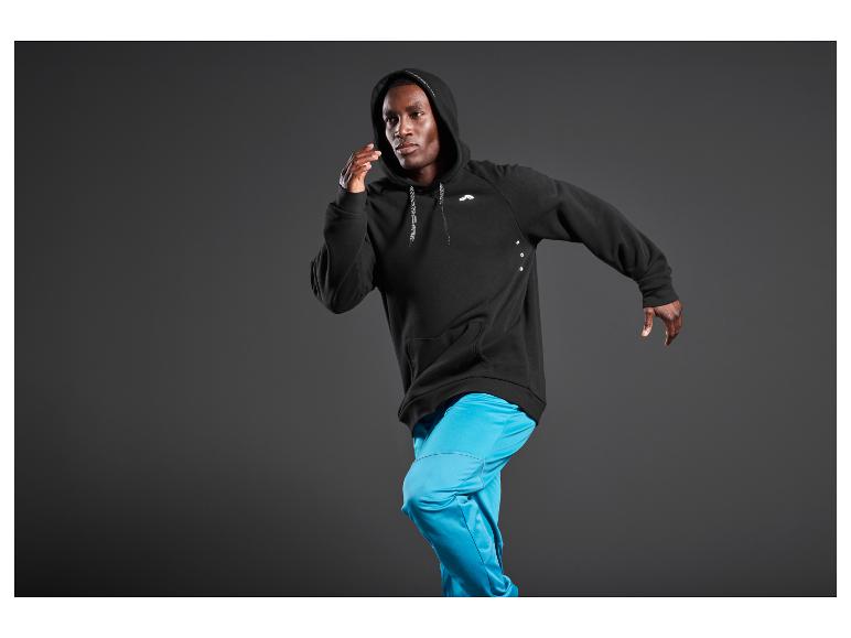 Un homme portant un sweat-shirt noir à capuche et un pantalon bleu.