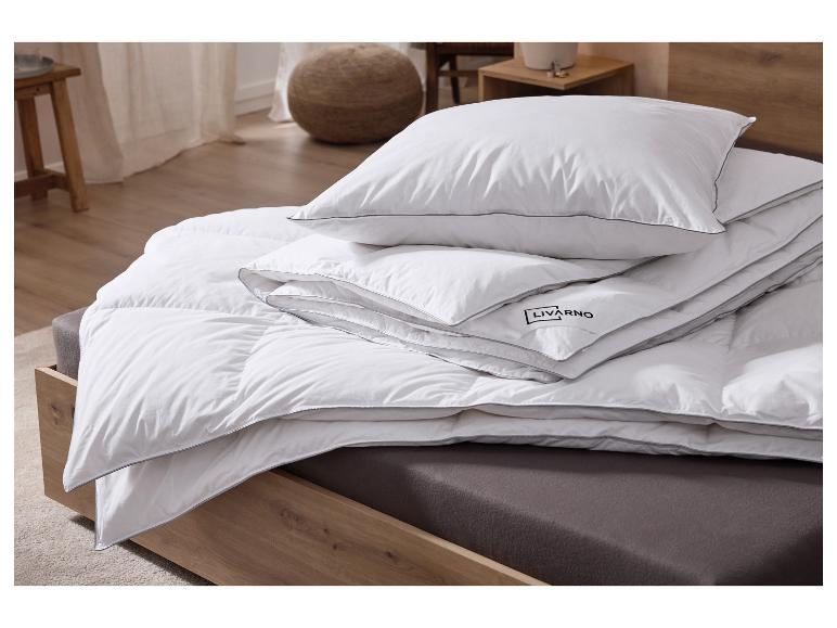 Oreiller et couette blancs avec bords gris sur un lit en bois.