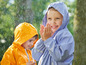 Deux enfants en imperméables jouent sous la pluie.
