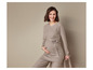 Une femme enceinte portant un pull et un pantalon en maille beige.
