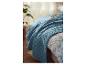 Couverture bleu et linge de lit fleuri sur un lit.