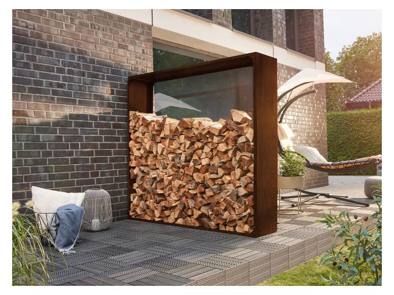 Range-bûches extérieur avec bois empilé, à côté d'un mur de briques et de mobilier de patio.