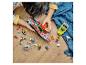 Enfant jouant avec des bateaux jouets et des figurines sur un plancher en bois.
