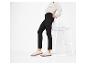 Une personne portant un pantalon noir, un sweat-shirt blanc et des baskets blanches, appuyée sur une chaise blanche.