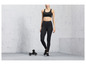 Une femme en soutien-gorge de sport et leggings avec des haltères.