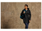 Une femme portant une veste noire et un sac à dos bleu.
