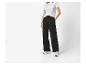 Femme en t-shirt blanc et pantalon large noir, avec des baskets blanches.